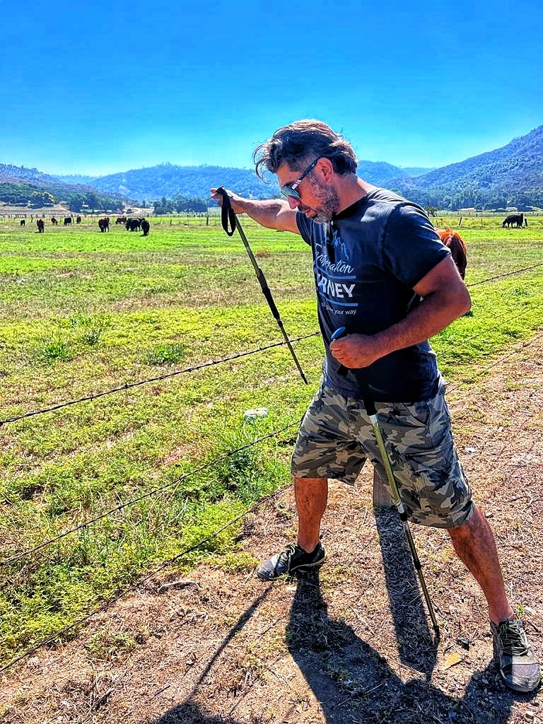 Cazonci Yacata walking with trekking poles beside a bright green mountain pasture