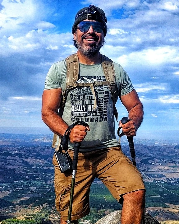 A hiker standing above a broad valley with trekking poles