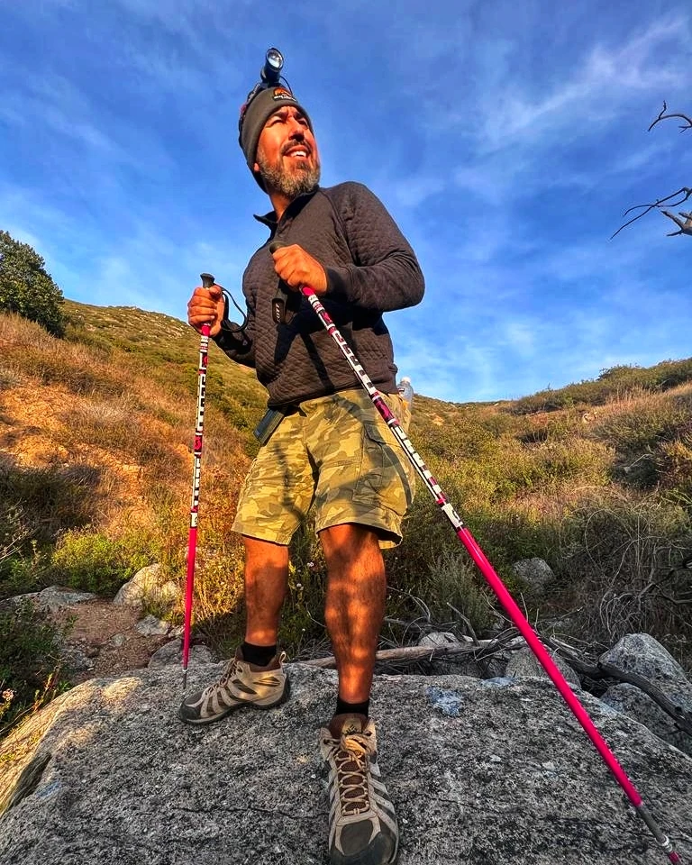 A hiker looking upward while climbing rocky terrain