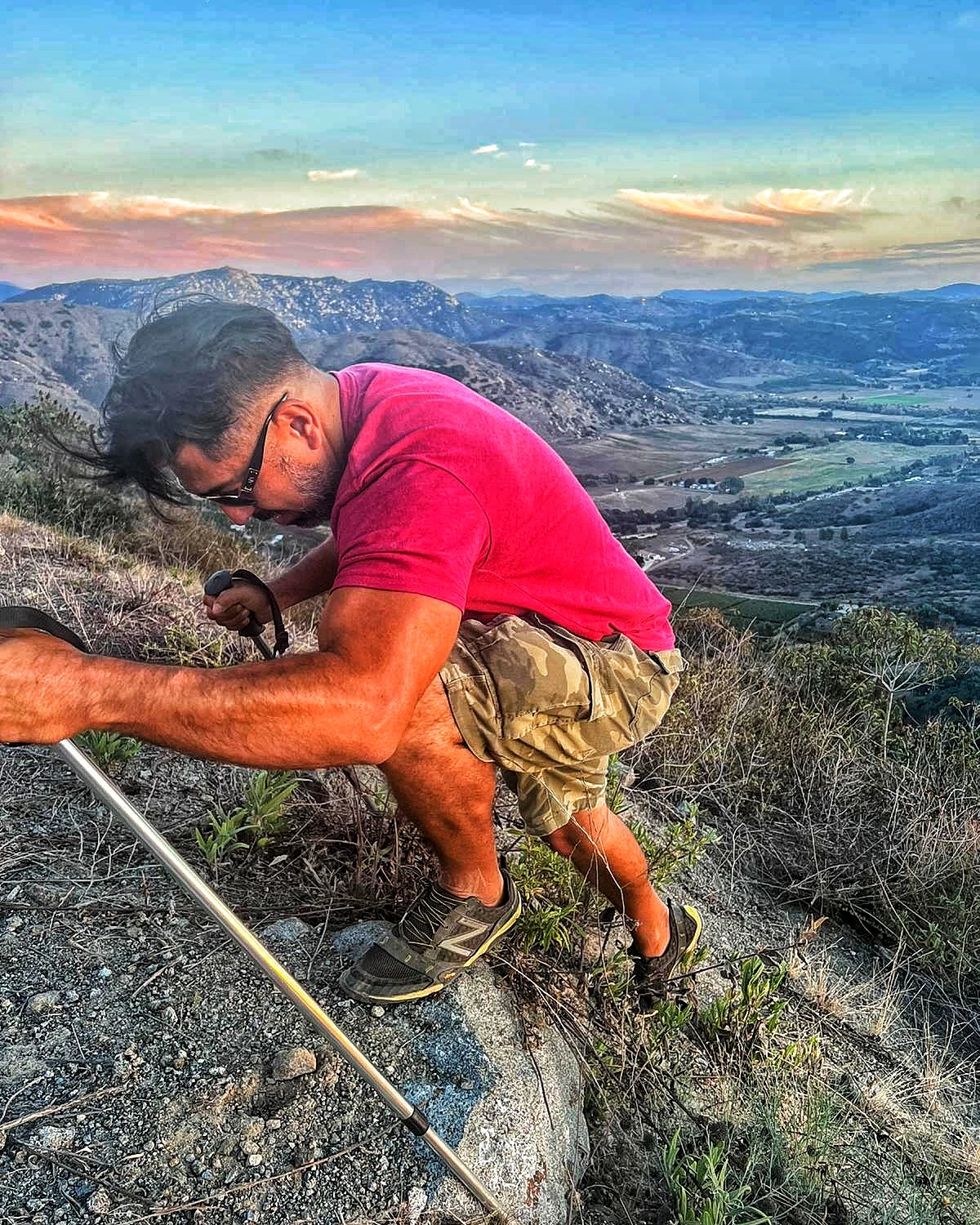 A hiker bracing with trekking poles on steep terrain